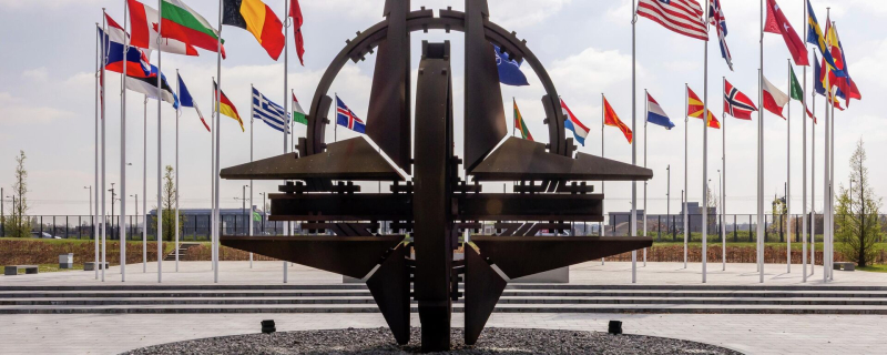 Флаги стран-участниц НАТО и эмблема альянса перед штаб-квартирой  НАТО в Брюсселе